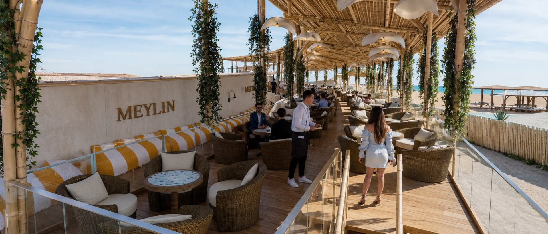 Terraza Meylin del beach club de AQUALODGE con sofás, vegetación y vista al mar, Tumbes